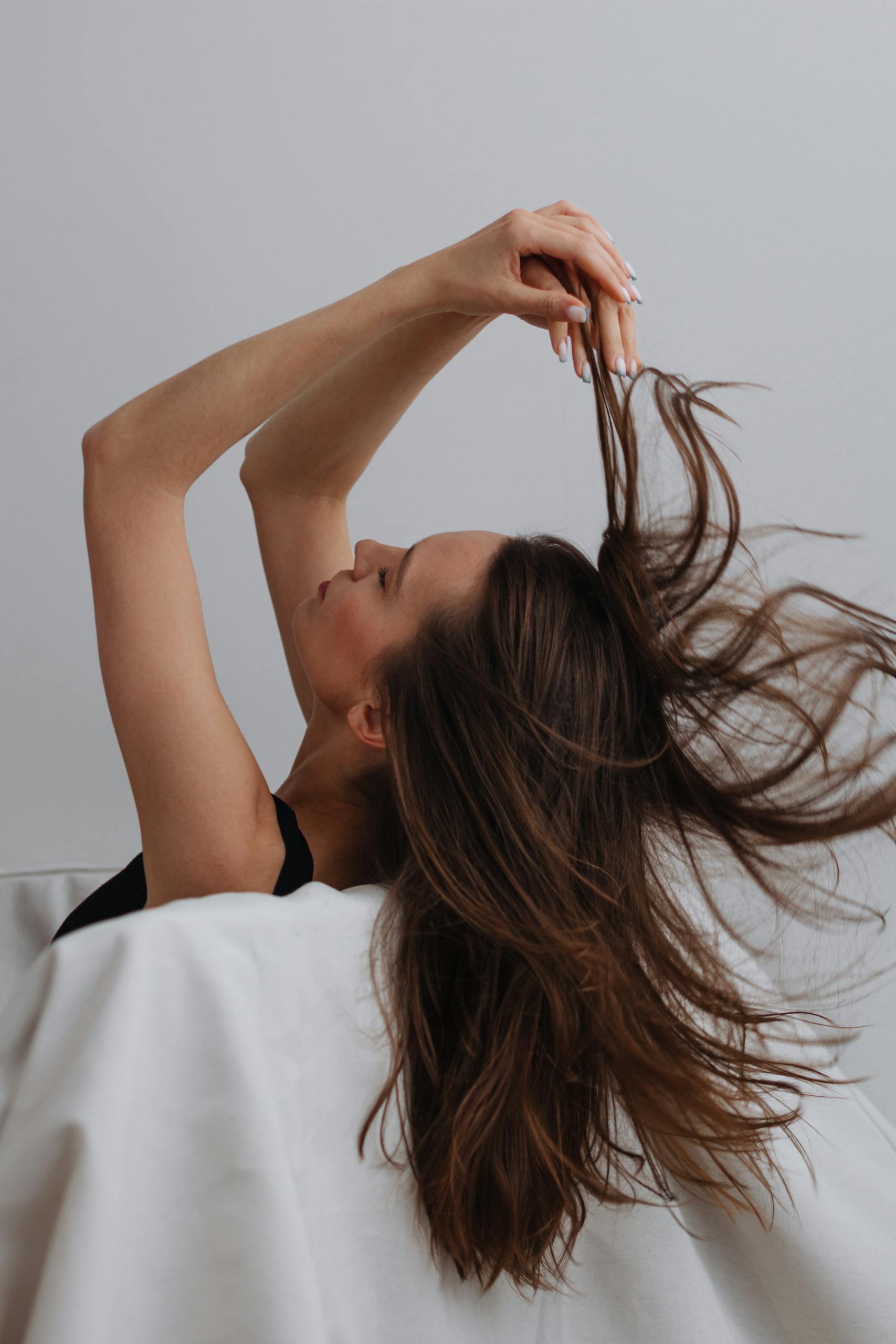 Stylish portrait of a woman running her fingers through her flowing brunette hair.